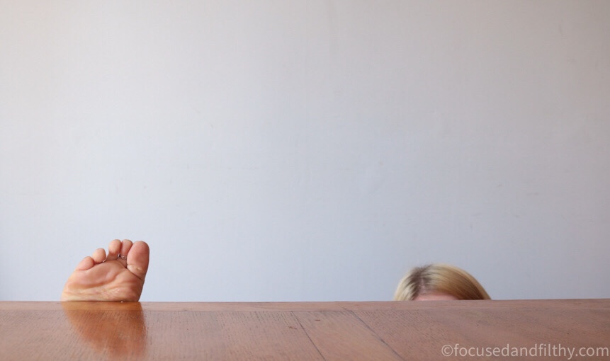 Colour photograph of a clear table top with just peaking over the top one set of toes and the top of my head  