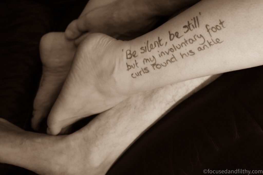 Black and white  photograph  of a  woman’s legs entwined with male legs and one ankle there is writing that says “be silent be still” but my involuntaryfoot curls round his ankle 