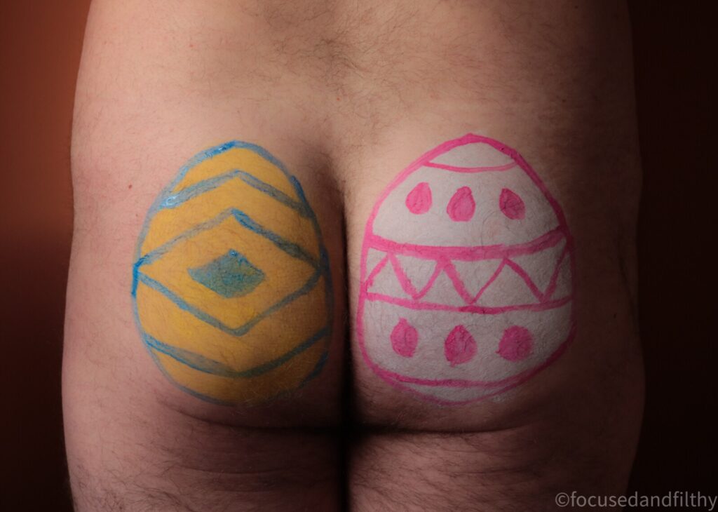 Close up colour photograph of a blokes naked arse with an Easter egg painted on each butt cheek  