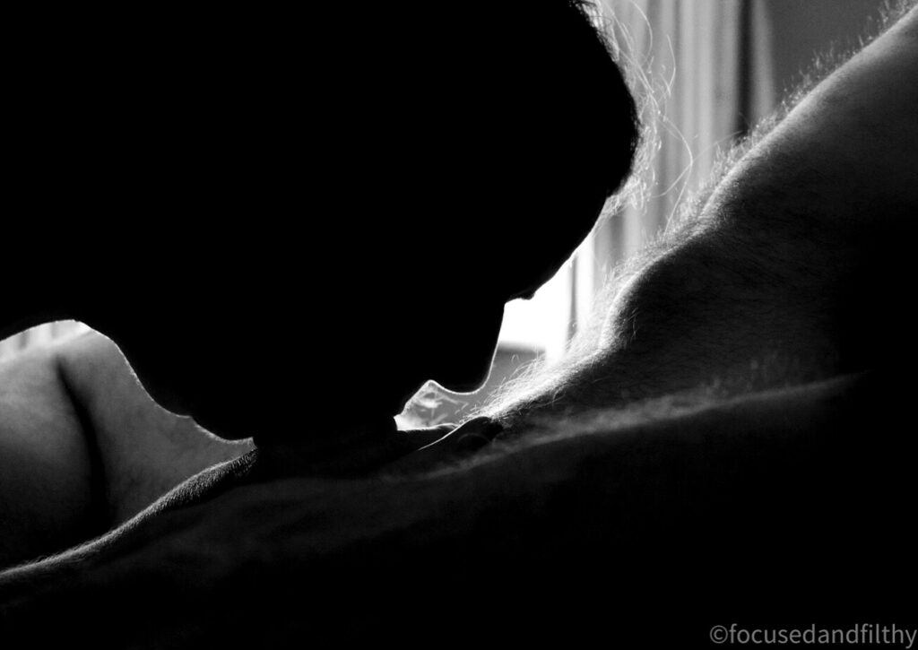 Black and white photograph of a woman in silhouette swallowing a whole cock 