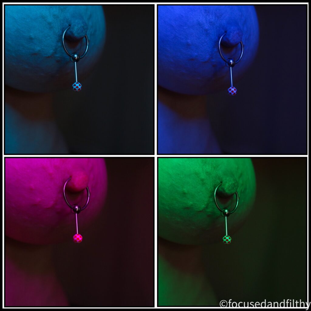 A collage of four images of my naked left breast with a nipple ring in that has a drop bar below it and the ball on the end is white with little pink hearts on it. Each of the four images has a difficult colour light for taking it. Turquoise, Blue, Pink and Green. It has a pop art look about it. 
