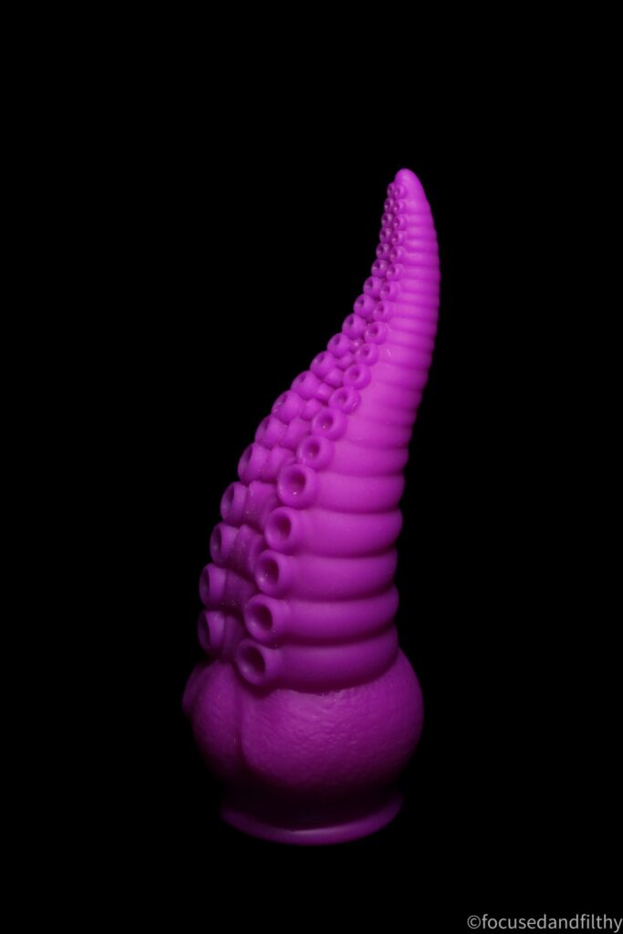 A photograph of a large fat purple tentacle dildo against a black background 