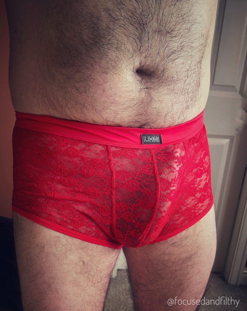 Close up photo of my fella’s middle.  He’s just wearing a pair of red lace boxer shorts and his very large erect penis is rather obvious through them. 