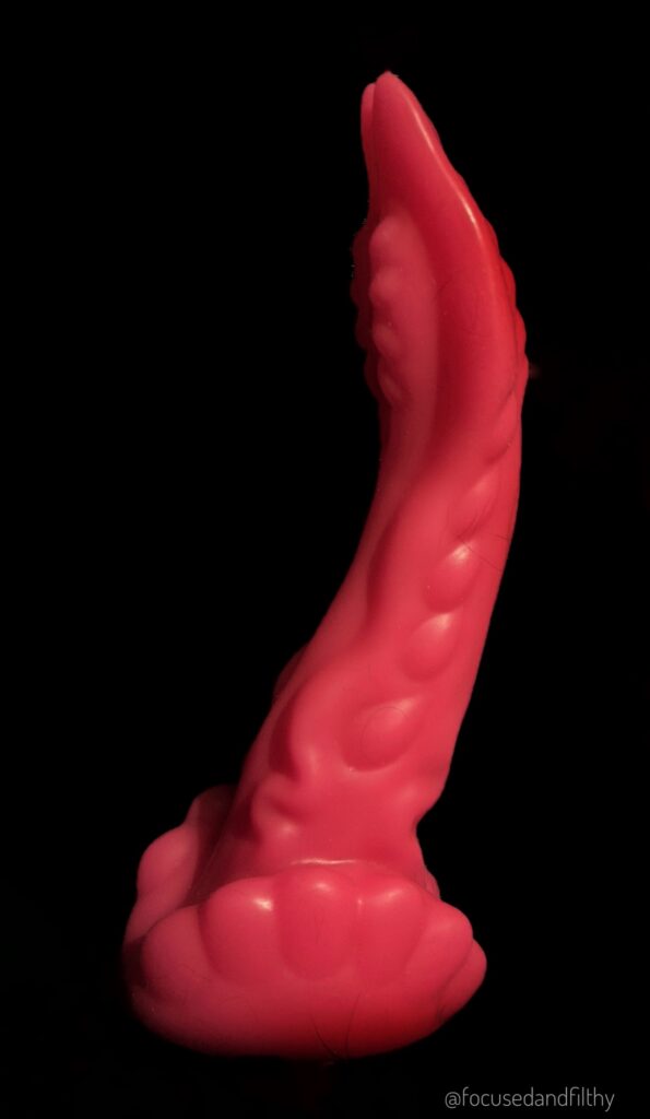 A large pink alien dildo that is curved and lumpy at the top like a weird snake shape 